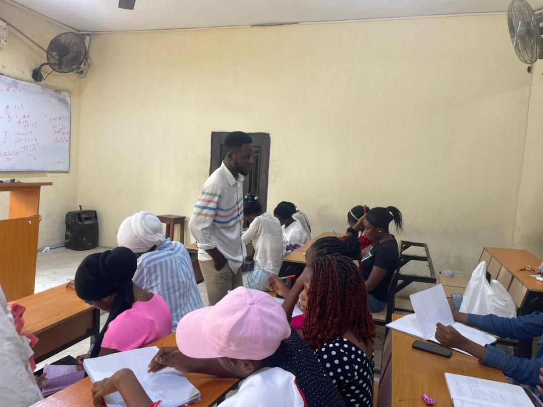 A tutor moving between desks in a busy classroom