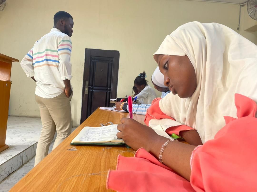 A tutor standing beside students as they work