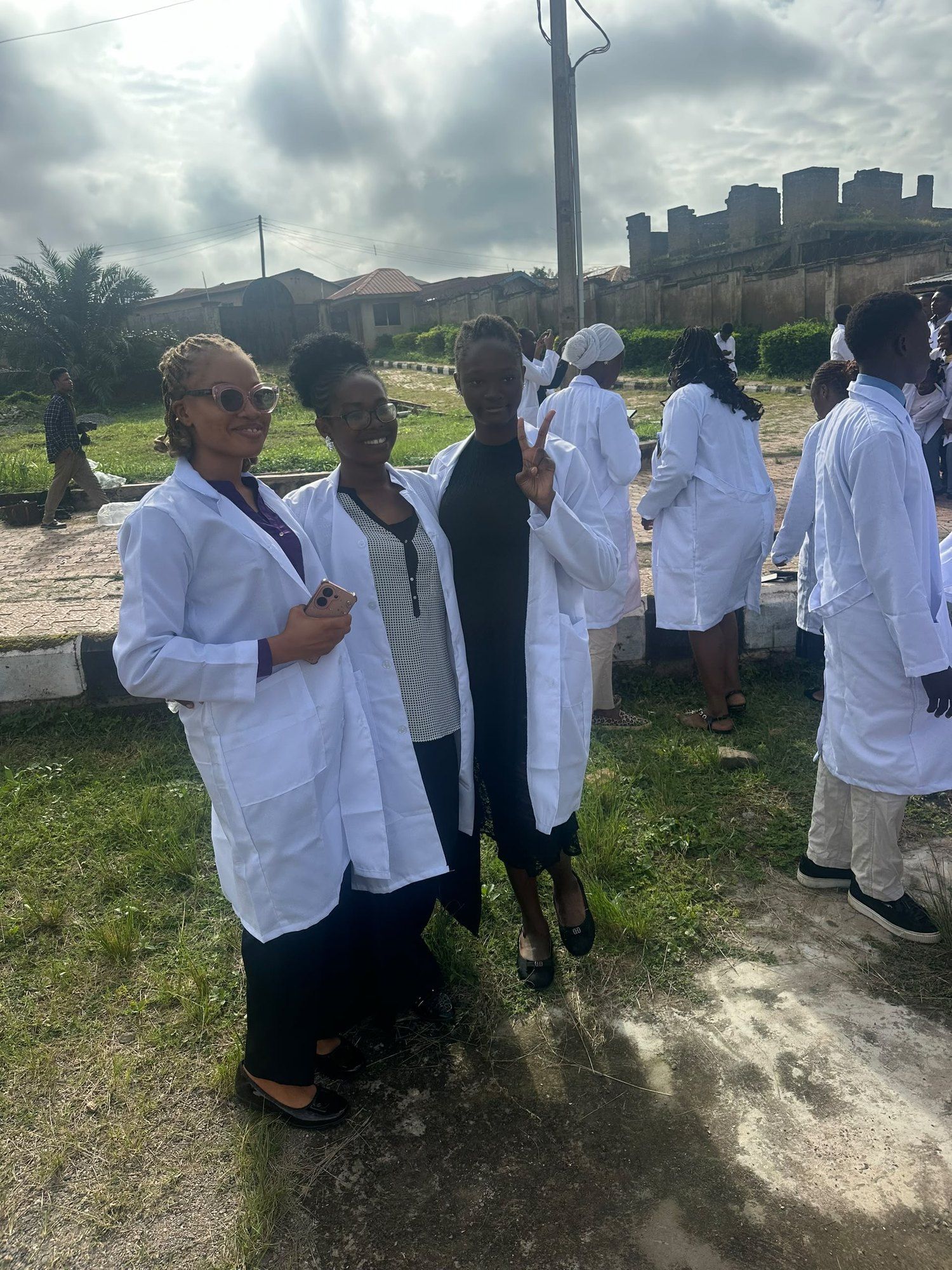 Students in white lab coats standing on a campus lawn