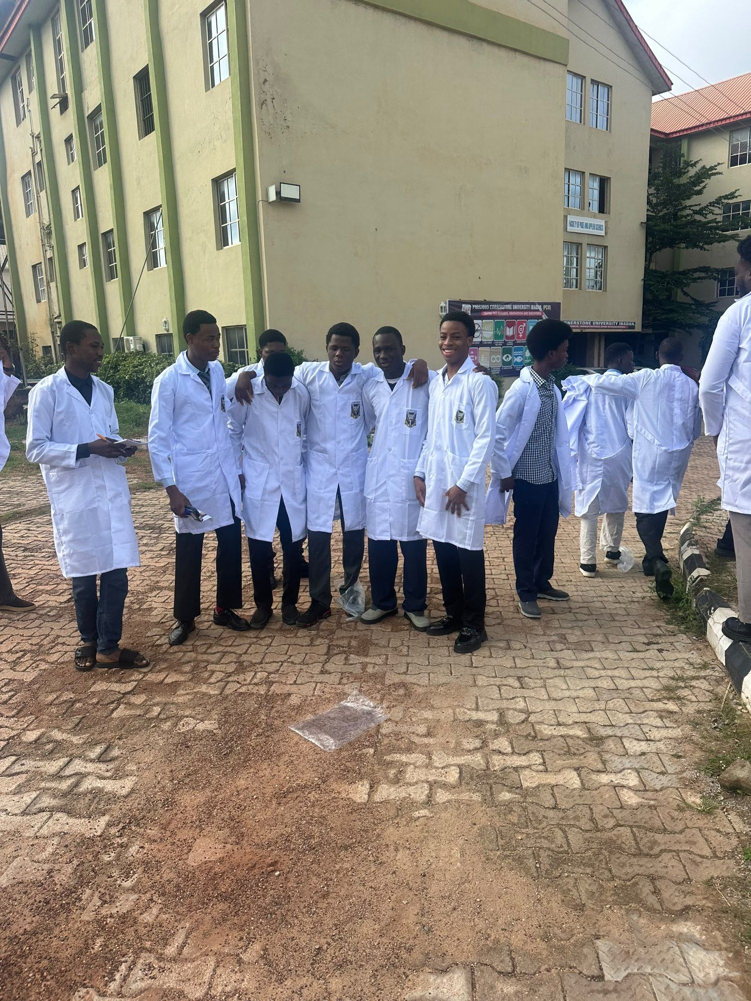 A group of students in white lab coats outside a campus building