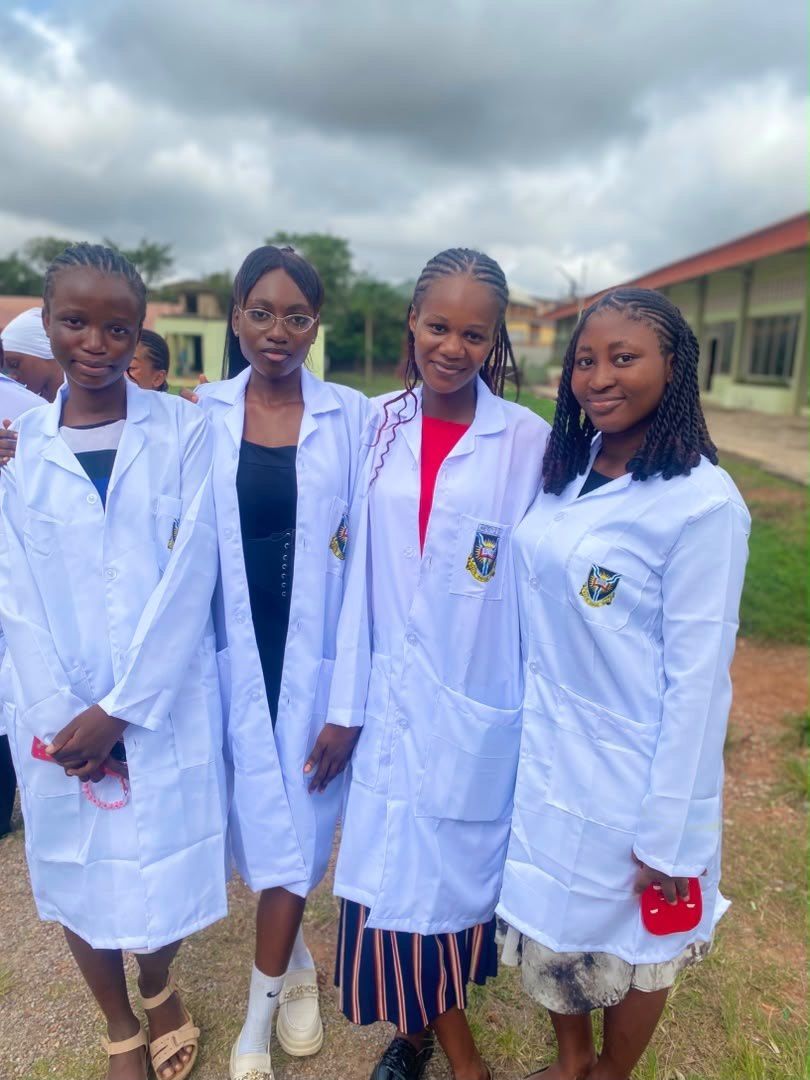 Four students in white lab coats standing outdoors