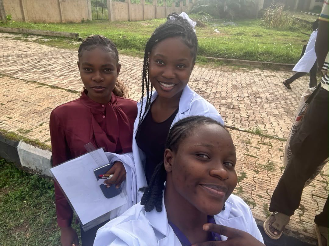 Three students smiling outdoors on campus