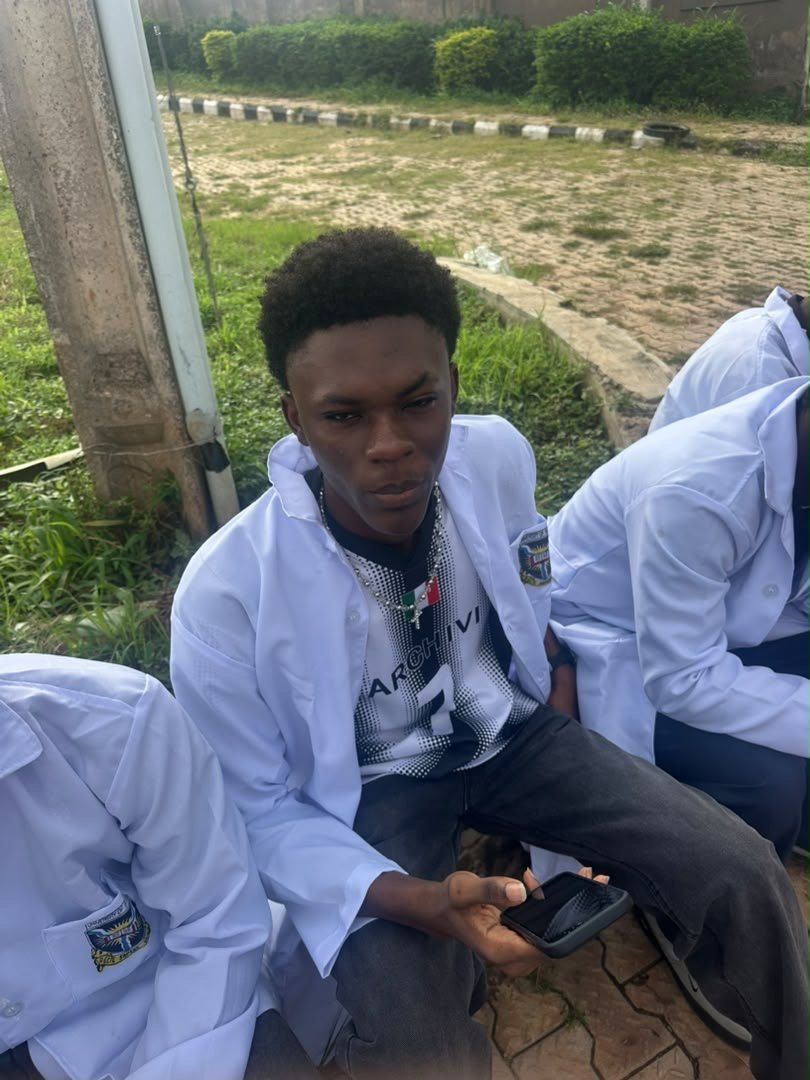 A student in a white lab coat seated outdoors